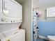 Bathroom with a washer/dryer combo, blue and white walls, and shower with cartoon whale curtain at 731 Guernsey St, Orlando, FL 32804