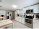 White kitchen with stainless appliances and a dining table on gray wood-look tile at 731 Guernsey St, Orlando, FL 32804