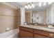 Bathroom featuring dual sinks, granite countertops, a bathtub, and neutral tiling at 8941 Bismarck Palm Rd, Kissimmee, FL 34747