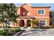 Inviting two-story townhome featuring a terra cotta exterior, arched doorways, and lush landscaping at 8941 Bismarck Palm Rd, Kissimmee, FL 34747