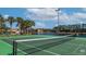 Community tennis court with green surface, net, and surrounding landscaping, ideal for recreational play and exercise at 8941 Bismarck Palm Rd, Kissimmee, FL 34747