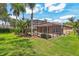 Backyard with a screened pool enclosure, lush landscaping, and a well-manicured lawn at 10161 Sandy Marsh Ln, Orlando, FL 32832