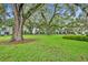 Wide, green lawn surrounded by large trees with Spanish moss and townhouses with screened patios in the background at 1150 Vineland Pl, Lake Mary, FL 32746