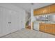 Kitchen with white appliances, wood cabinets, tile flooring, and view to stairs at 1150 Vineland Pl, Lake Mary, FL 32746