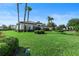 Front yard showcasing lush green lawns, manicured bushes, with a glimpse of the house and palm trees at 11706 Waterstone Loop Dr, Windermere, FL 34786