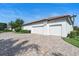 Three-car garage of a white house with a paved driveway on a sunny day with green landscaping at 11706 Waterstone Loop Dr, Windermere, FL 34786