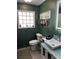 Stylish bathroom with a glass block window, bright white fixtures, and a vessel sink on a teal vanity at 1203 Monterey Dr, Eustis, FL 32726