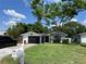 Inviting single-story home with a manicured lawn, mature tree, and a screened-in garage at 1203 Monterey Dr, Eustis, FL 32726