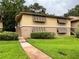 Tan two-story home with dark shutters and a sidewalk leading to the entrance at 130 Jasmine Woods Ct # 3D, Deltona, FL 32725