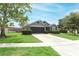 Beautifully landscaped home featuring a lush green lawn, mature trees, and a welcoming two-car garage at 1825 Needham Rd, Apopka, FL 32712