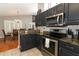 Modern kitchen with stainless steel appliances, granite countertops, and dark cabinetry adjacent to the dining room at 1825 Needham Rd, Apopka, FL 32712