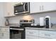 Close-up of modern kitchen appliances, granite countertops, and white cabinetry with stainless steel hardware at 2024 Sw 153Rd Loop, Ocala, FL 34473
