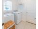 Bright laundry room featuring modern washer and dryer, overhead shelving, and door at 26271 Feathergrass Cir, Leesburg, FL 34748