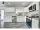 Updated kitchen features white cabinets, stainless steel appliances, granite countertops, and gray wood-look floors at 2736 Shannon Rd, Orlando, FL 32806
