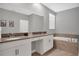 Bright bathroom featuring double sinks, a tiled bath, and a large mirror for added convenience at 2821 Bookmark Dr, Kissimmee, FL 34746