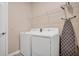 Bright laundry room with white washer and dryer, shelving, and ironing board at 2821 Bookmark Dr, Kissimmee, FL 34746