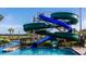 A large blue and green winding waterslide emptying into a sparkling pool, surrounded by lush greenery and lounge area at 2821 Bookmark Dr, Kissimmee, FL 34746