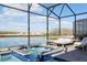 Tranquil pool and spa with a screened enclosure, offering views of the water and seating at 2836 Simile St, Kissimmee, FL 34746
