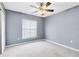 A gray bedroom featuring neutral carpet, a ceiling fan, and a window with blinds at 3813 Goldenglow Dr, Orlando, FL 32828