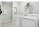 Clean laundry room with white washer and dryer, shelving, and tile flooring in a light, airy space at 439 Shoreview Sands Ave, Mascotte, FL 34753
