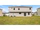 View of the back of the house with a sliding glass door and a grassy lawn at 4905 Pall Mall E St, Kissimmee, FL 34758