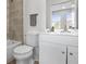 Bathroom with a tile wall, white cabinets, a large mirror, and a white toilet at 4905 Pall Mall E St, Kissimmee, FL 34758
