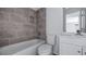 Modern bathroom features tub, shower with gray tile surround and a white vanity at 4905 Pall Mall E St, Kissimmee, FL 34758
