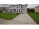 Inviting two-story home featuring a well-maintained lawn, attached garage, and neutral gray color scheme at 4905 Pall Mall E St, Kissimmee, FL 34758