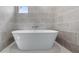 Modern bathroom with a luxurious white standalone soaking tub and gray tiled wall at 4905 Pall Mall E St, Kissimmee, FL 34758