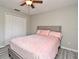 This bedroom has gray wood floors, a ceiling fan, large wardrobe, window, and a soft pink comforter at 506 Harbor Winds Ct, Winter Springs, FL 32708