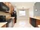 Open kitchen featuring wood cabinets, black appliances, and neutral tile flooring at 506 Harbor Winds Ct, Winter Springs, FL 32708