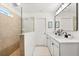 Bathroom with double vanity sinks, white cabinets, and a tiled shower with glass door at 5458 Carrara Ct, St Cloud, FL 34771