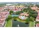 An aerial shows tennis court, pond, and a pool at an area community with lush greenery at 625 Pavia Loop, Lake Mary, FL 32746