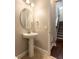 Bathroom with dark hardwood floors and neutral walls, features a pedestal sink, mirror, and modern light fixtures at 625 Pavia Loop, Lake Mary, FL 32746