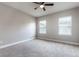 Bright, carpeted bedroom featuring a ceiling fan and two large windows with blinds at 625 Pavia Loop, Lake Mary, FL 32746