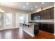Well-lit kitchen features stylish lighting, hardwood floors, stainless steel appliances and dark-stained wood cabinets at 625 Pavia Loop, Lake Mary, FL 32746