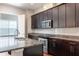 Modern kitchen with granite countertops, stainless steel appliances, tile backsplash, and dark wood cabinets at 625 Pavia Loop, Lake Mary, FL 32746
