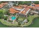 Stunning aerial view of resort featuring a large pool, lush landscaping, and Mediterranean-style architecture near a tranquil lake at 636 San Augusto Dr, Kissimmee, FL 34759
