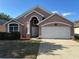 Charming single-Gathering home with a two-car garage and manicured landscaping under a bright blue sky at 6625 Cherry Grove Cir, Orlando, FL 32809