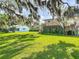 Expansive backyard with mature trees framing the house, offering a private and picturesque setting at 721 Fairway Dr, New Smyrna Beach, FL 32168