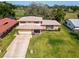 Aerial view of a house with a well-manicured lawn and a spacious driveway and golf course in back at 721 Fairway Dr, New Smyrna Beach, FL 32168