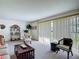 Bright living room featuring a large window, comfortable seating, and decorative shelves with Gathering photos at 721 Fairway Dr, New Smyrna Beach, FL 32168