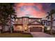 Charming two-story home with well-manicured lawn, stone accents and two-car garage, set against a colorful sunset sky at 8180 Valhalla Ter, Reunion, FL 34747