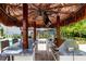 This outdoor kitchen is equipped with a grill, TV, and seating beneath a tiki hut for outdoor dining at 8180 Valhalla Ter, Reunion, FL 34747