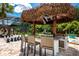 An outdoor kitchen with bar stool seating under a tiki hut overlooks a large chess set and pool area at 8180 Valhalla Ter, Reunion, FL 34747