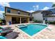 Inviting backyard pool and spa with lounge chairs, set against the backdrop of a tan two-story home and a blue sky at 8180 Valhalla Ter, Reunion, FL 34747