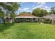 A view of the home's backyard from the lawn, featuring lush green grass and mature trees at 916 Glendale St, Orlando, FL 32807