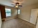 Neutral bedroom features carpet, ceiling fan, and natural light from two windows at 10631 Village Lake Rd, Windermere, FL 34786
