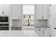 Close-up of a bright kitchen with white cabinets, quartz countertops, stainless steel appliances, and a farmhouse-style sink at 117 E Concord St # 7, Orlando, FL 32801