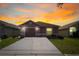 Charming single-story home with a well-manicured lawn and a long driveway, all under a beautiful sunset sky at 125 Owenshire Cir, Kissimmee, FL 34744